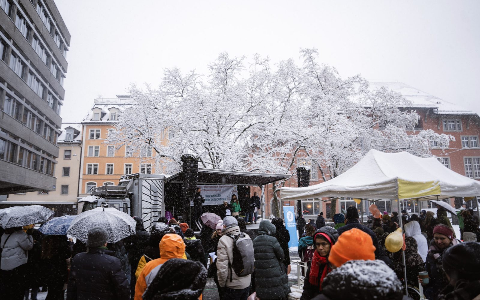 Winterliche Kundgebung mit Bühne und Publikum im Schneetreiben.